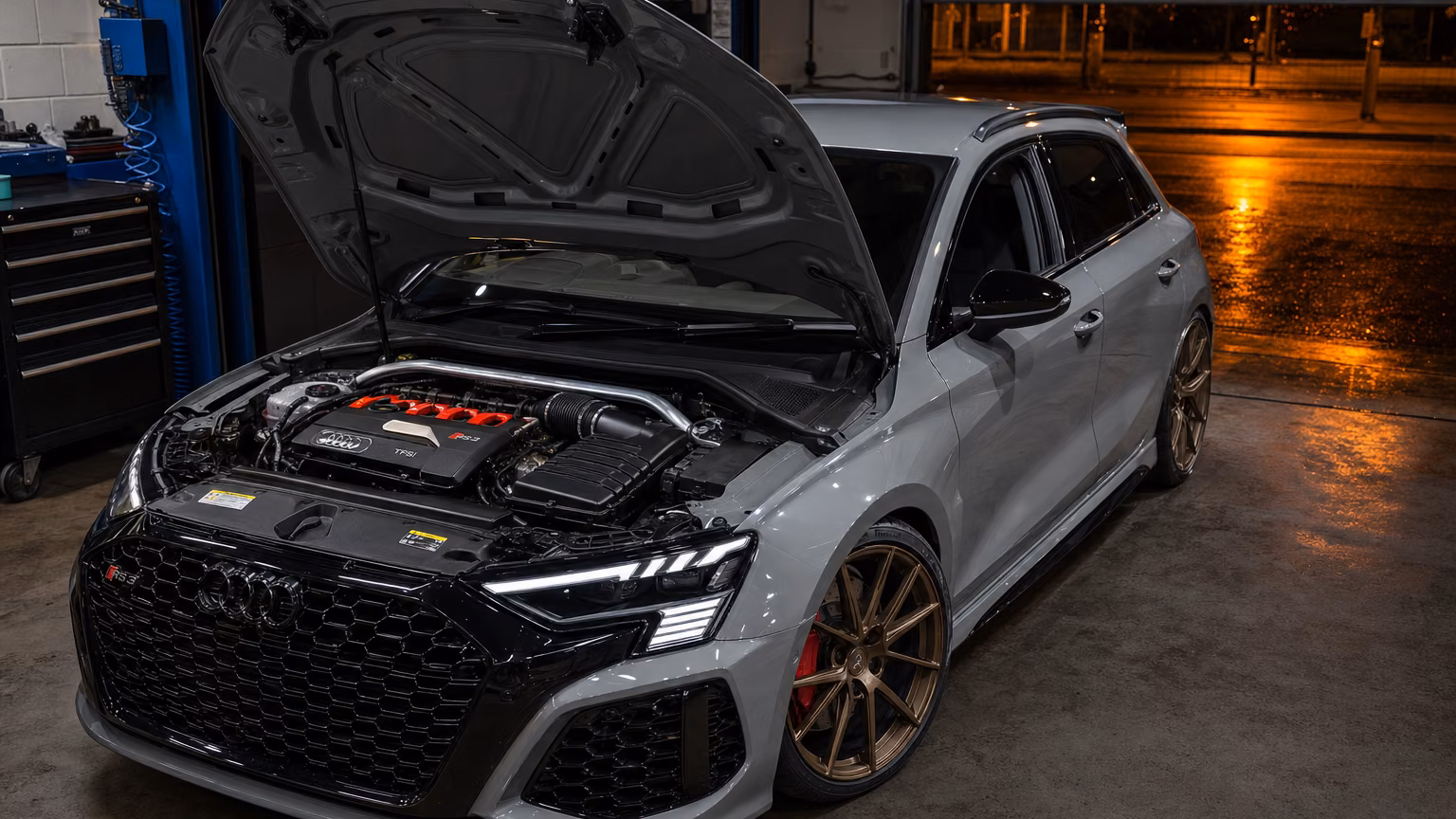 An Audi RS3 on the floor of the Precision Autoworks workshop in Glasgow, bonnet up over the engine bay.